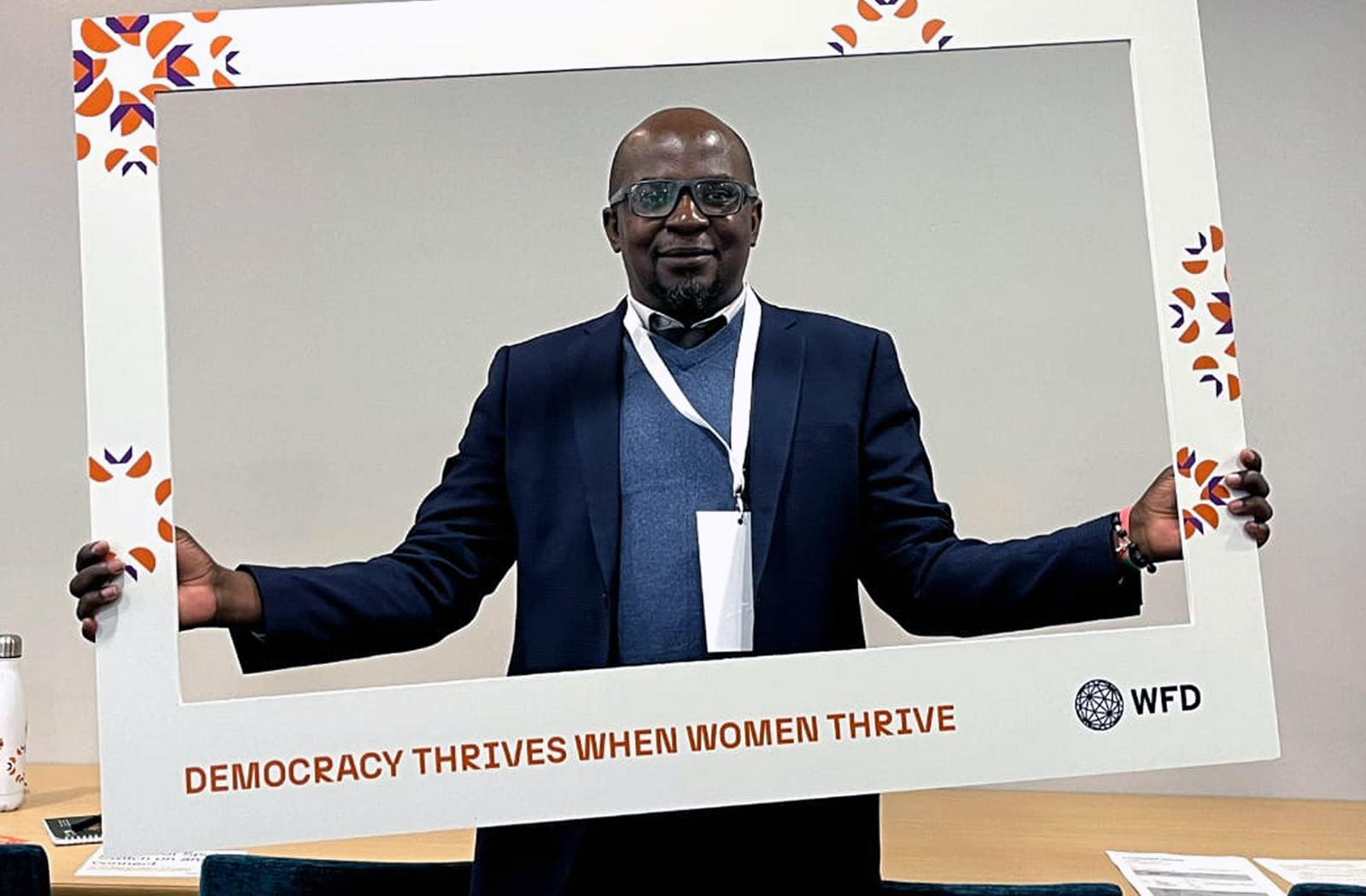 Viwemi Chavula in cut out sign reading democracy thrives when women thrive